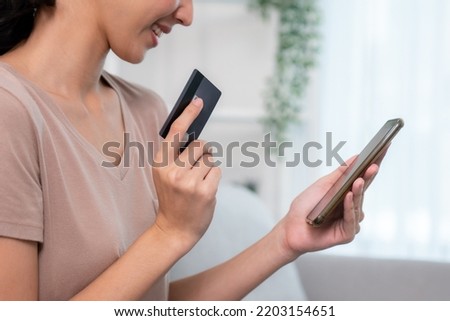 Contented young woman eagerly makes an online purchase using her smartphone. E-commerce business, online purchasing.