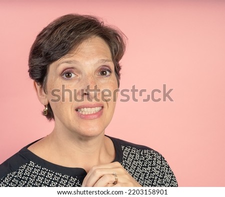 Brunette woman in her 50s in the studio with a pink background