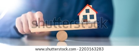 Wooden Seesaw House Balance. Real Estate Leverage Royalty-Free Stock Photo #2203163283