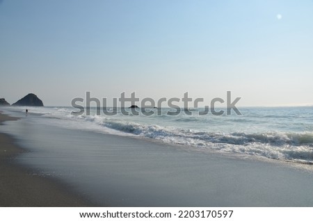 Beautiful waves coming in and going out with the sand and rocks in the picture.  The white surf against blue water and brown sand.