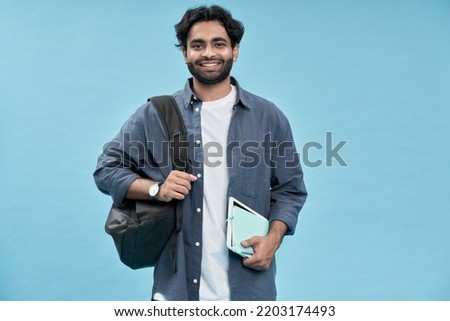 Smiling happy arab young man student holding backpack standing isolated on blue background. Business education concept, remote online learning and elearning, distance studying, scholarship programs.