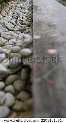 White pebbles with black moss wall on the right in the photo perspective