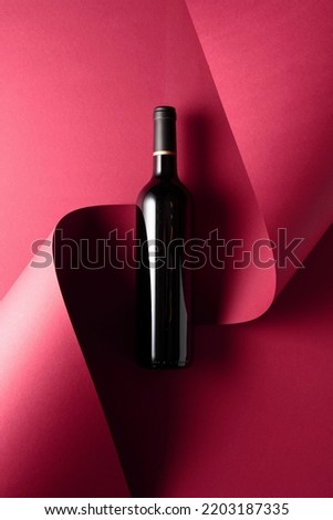 Bottle of red wine on a red background. Copy space for your text, top view.