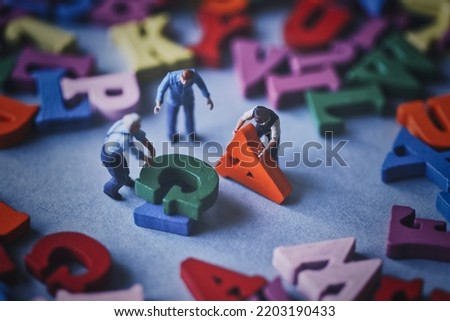 Miniature people carrying colorful alphabets