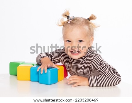 Cute little girl plays with blocks on a white background