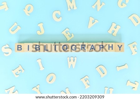 Bibliography part of a book concept. Wooden blocks typography word flat lay in blue background Royalty-Free Stock Photo #2203209309