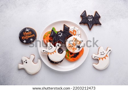 Halloween gingerbread cookies on white plate on stone background. Bright homemade cookies for Halloween party