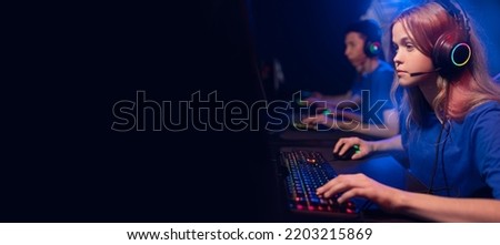 Streamer young woman professional gamer playing online games computer with headphones. Concept banner esport, neon color soft focus.