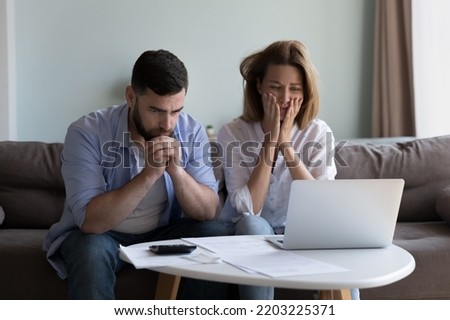 Frustrated worried millennial husband and wife reading bankrupt message, blocked account notice, feeling concerned about overspent budget, lack of money, getting bad news, paying bills Royalty-Free Stock Photo #2203225371
