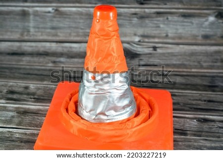 A car traffic cone isolated on wooden background used as transportation safety, careful driving and road repair concept, selective focus of a traffic funnel cone used as a safety measure