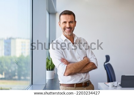 Portrait of smiling mid adult businessman standing at corporate office Royalty-Free Stock Photo #2203234427