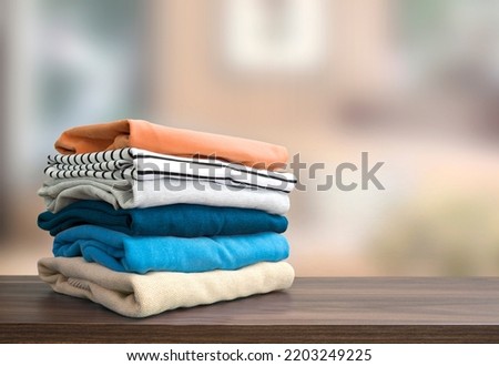 Stack of folded clothing, autumn colors stacked sweaters.Heap of clothes.Laundry,household on wooden table empty space. Royalty-Free Stock Photo #2203249225
