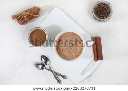 Coffee drink with milk and whipped cream, cappuccino coffee, latte, cinnamon, coffee beans on a gray concrete table, modern coffee shop advertisement, selective focus, top view, space for text,
