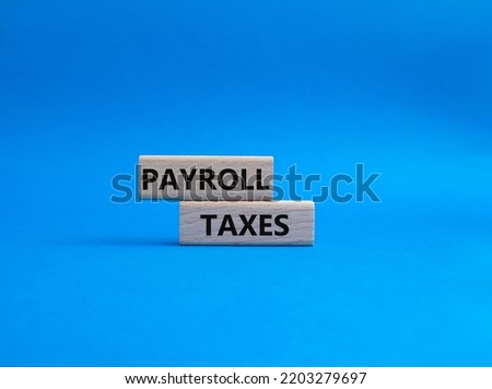 Payroll taxes symbol. Concept word Payroll taxes on wooden blocks. Beautiful blue background. Business and Payroll taxes concept. Copy space