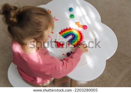 A little girl playing with rainbow from play dough for modeling. Art Activity for Kids. Fine motor skills. Sensory play for toddlers.	 Royalty-Free Stock Photo #2203280005