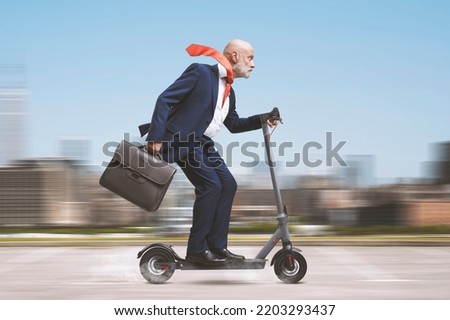 Senior corporate businessman riding an electric scooter in the city Royalty-Free Stock Photo #2203293437