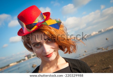 portrait of a cheerful clown with the red hat on the background of blue sky