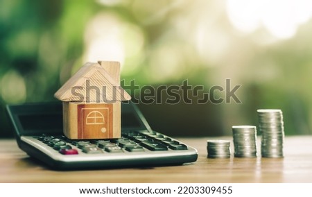 House is placed on the calculator and coins placed on table. concept calculating to buy a home. planning savings money of coins to buy a home concept for property, mortgage, real estate to buy a home.