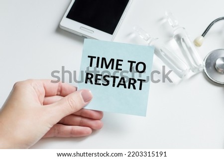 TIME TO RESTART text on a blue card in the doctor's hand against the background of a table with medicaments