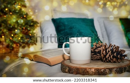 Christmas Tree with decorations on Christmas bokeh lights background. White cup or mug, mockup. Christmas and new year holidays concept                               