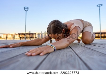 Young sporty woman training in outdoor, working out at animal flow style, making front kick through position.  Royalty-Free Stock Photo #2203325773