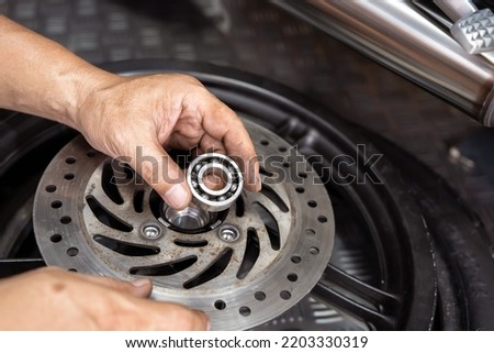 Mechanic check and replace Motorcycle wheel bearings , working in garage . repair and  maintenance motorcycle concept .selective focus Royalty-Free Stock Photo #2203330319