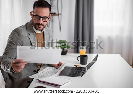 Focused young adult businessman, making sure his company is earning enough money. Royalty-Free Stock Photo #2203330431