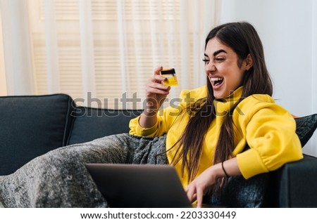 Joyful adult young woman, purchasing items online, using her credit card.