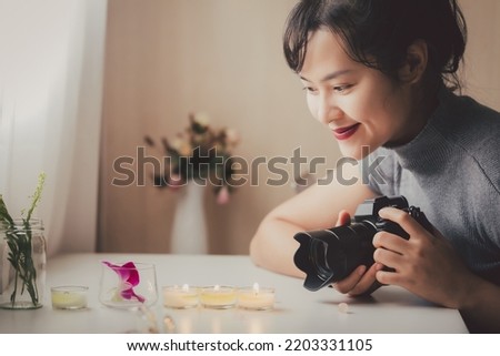 Close up Asian female freelancer photographing with a camera in casual clothes. Female photographer working in a studio. Hobby side hustle job creative artist. Content creator for commercial company.