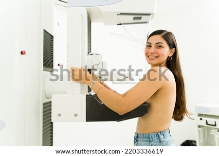 Portrait of a happy hispanic woman at the imaging diagnostic lab smiling while getting a mammogram during a breast cancer awareness program