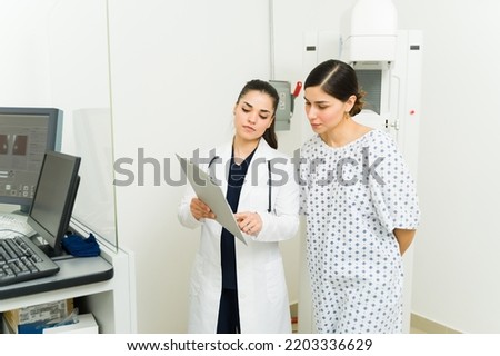 Female radiologist giving the medical results of the mammogram x-ray exam to a young woman at the hospital 