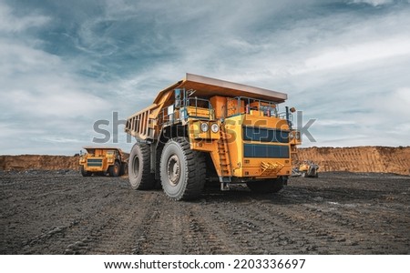 Large quarry dump truck. Big yellow mining truck at work site. Loading coal into body truck. Production useful minerals. Mining truck mining machinery to transport coal from open-pit production Royalty-Free Stock Photo #2203336697