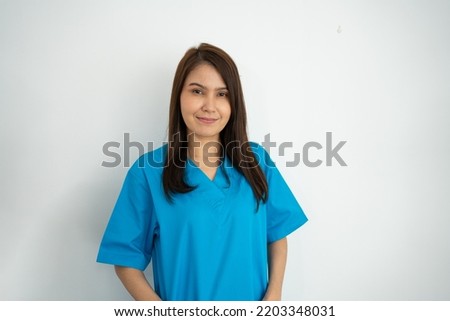 Portrait Of confident, happy, and smiling Asian medical woman doctor or nurse wearing blue scrubs uniform over isolated white background