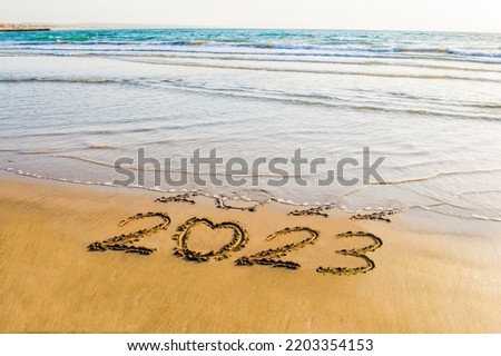 Happy New Year 2023 text on the sea beach. Abstract background photo of coming New Year 2023 and leaving year of 2022