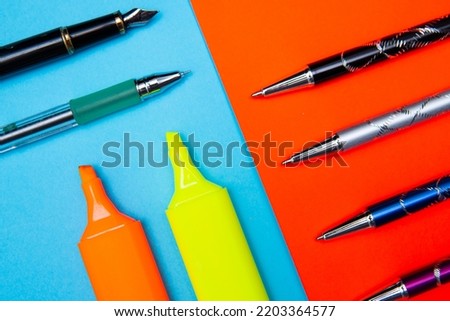 colored highlighters and various pens on a colored background. School or office supplies in a flat lay photo