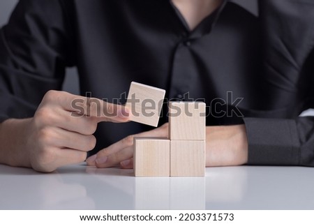 The man's  hand placed a wooden cube on table.  Business strategy and  plan. Copy space.  Mockup for letters, symbol, picture text, word, idea, concept
