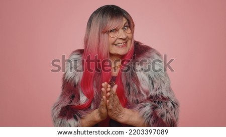 Sneaky cunning woman with tricky face gesticulating and scheming evil plan, thinking over devious villain idea, cunning cheats, jokes and pranks. Senior grandmother on pink studio background indoors Royalty-Free Stock Photo #2203397089