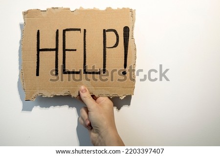 A woman's hand holds a piece of cardboard with the inscription HELP, Domestic violence concept.