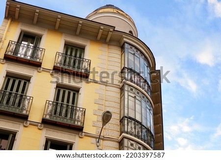 Rounded corner of historical classical building with elegant metallic balconies and windows with old wooden shutters. Classy Spanish architecture of Madrid, Spain.