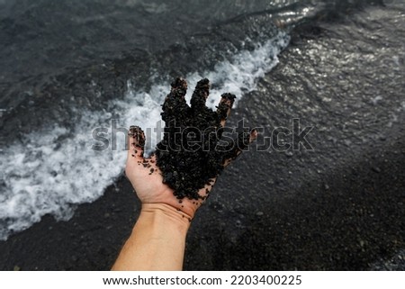 A girl holds a pebble from the beach against the background of moving waves. Top view