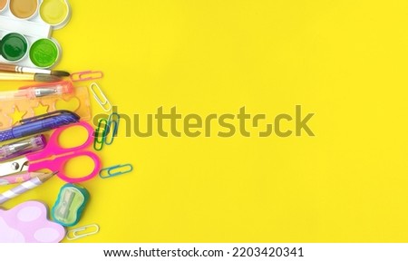 Top view layout of office supplies on a yellow background. pen, pencil, paints, brush, paper clips, sharpener close-up on a yellow background. Stationery