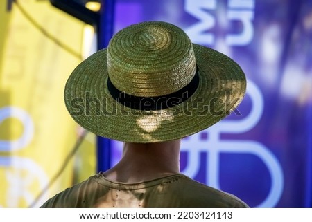 A photo of a lady with a summer sun hat with a black ribbon wrapped around it