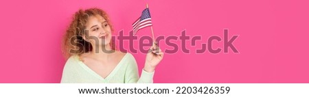 A young happy girl with a smile on her face holds an American flag in her hands. Symbol of patriotism and freedom.