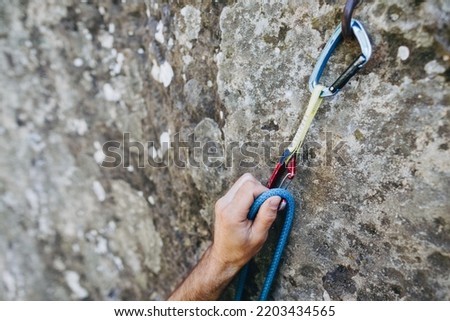 Close up of rock climber hand clipping rope in a quick draw caribener on a cliff face Royalty-Free Stock Photo #2203434565