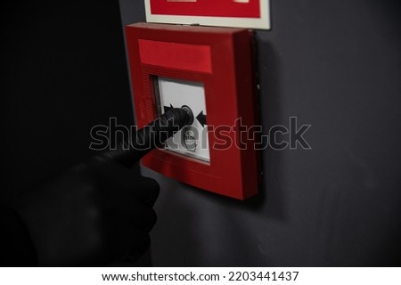Man in black gloves turning on the fire alarm