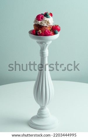 Beautiful muffin with delicious vegan cream, fresh berries on a decorative white pad . Place for your text. Sweet concept. Excellent image for dessert banners and advertisements. Desert background. 
