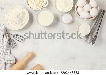 Frame for baking and making cake, bread, confectionery and ingredients for cooking, milk, flour, salt, sugar, eggs and cream on a concrete background with space for text, selective focus, top view