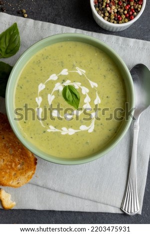 Horizontal image of bowl of pea soup with garnish, with toast and peppercorns on slate. Tasty home cooked food and healthy eating.