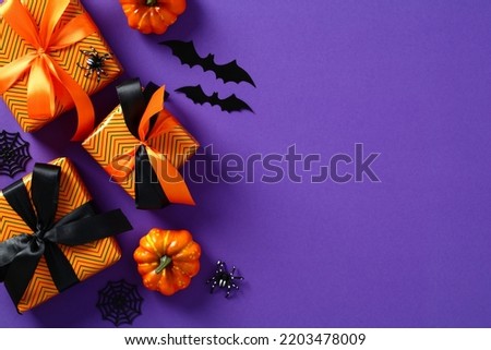 Happy Halloween holiday concept. Flat lay gift boxes, orange pumpkins, bats, spiders on purple background. Halloween greeting card template.