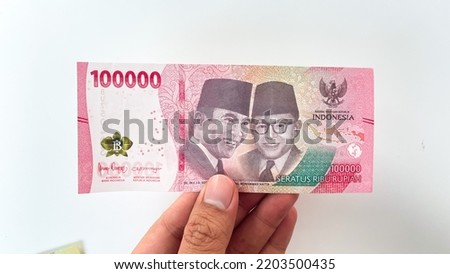 male hand holding new rupiah banknote in 2022. new 100,000 or hundred thousand rupiah denomination isolated on white background Royalty-Free Stock Photo #2203500435